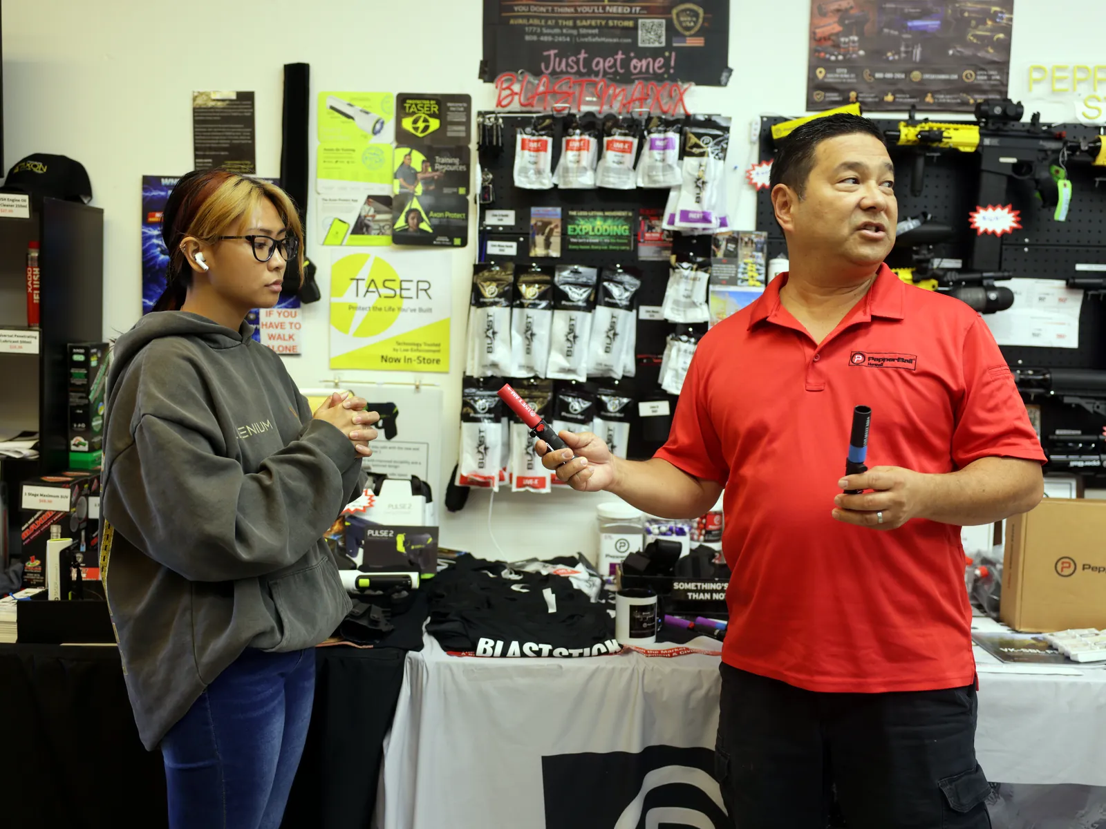 A staff member explaining a pepper spray option to a customer in the shop